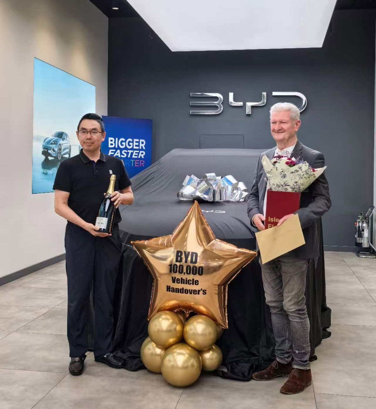 BYD executive vice president He Zhiqi (left) hands delivers a vehicle to a British customer.