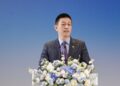 Nio founder William Li speaks at a flower-adorned podium during the Geely-Nio partnership event.