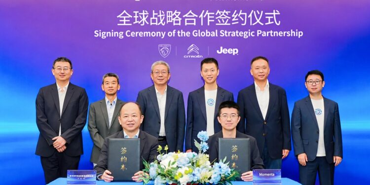 Momenta and DSAT representatives hold agreement folders at a global strategic partnership signing ceremony, with executives standing behind them.