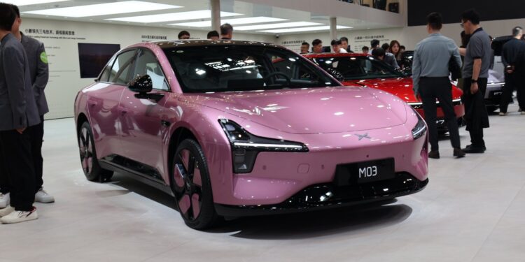 Pink Xpeng Mona M03 electric sedan on display at the Beijing Auto Show in April 2026, viewed from the front three-quarter angle.
