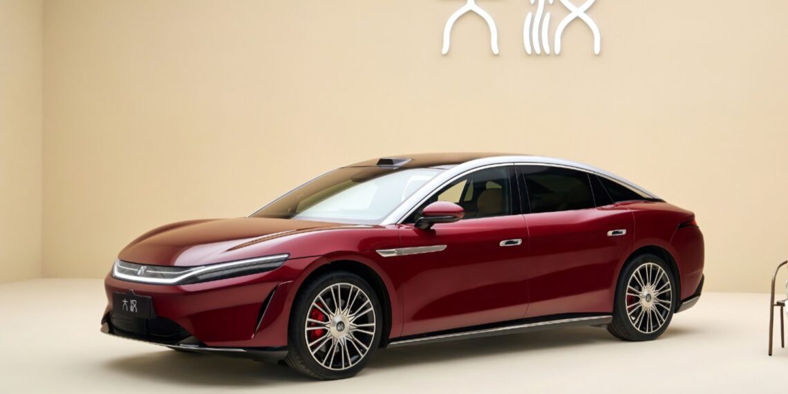 Red BYD Da Han flagship sedan with a silver roof, shown from a front three-quarter angle indoors.