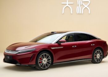 Red BYD Da Han flagship sedan with a silver roof, shown from a front three-quarter angle indoors.